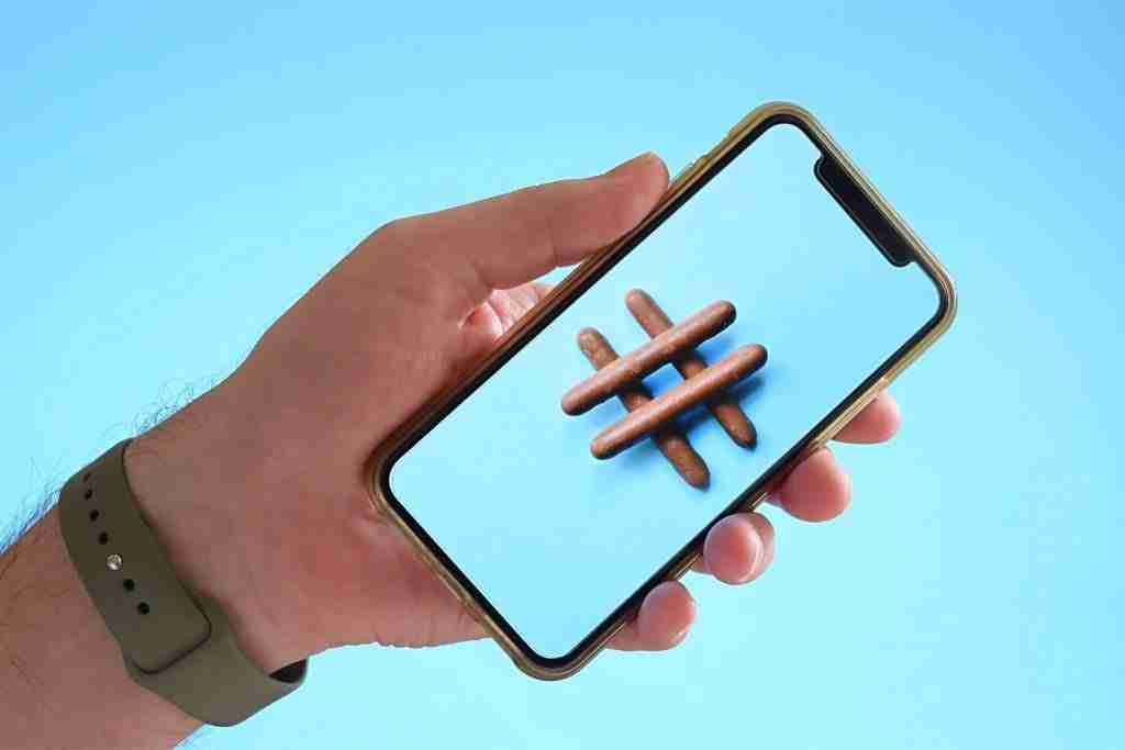 Hand holding a smartphone with hashtag on screen
