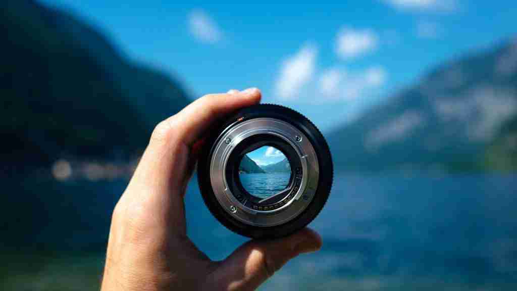 Hand holding a lens with a lake in the background