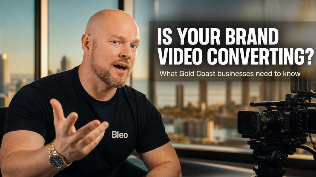 Luke Houlihan from Bleo Media excited and gesturing toward camera in front of Gold Coast skyline with video production camera, text overlay reading Is Your Brand Video Converting?
