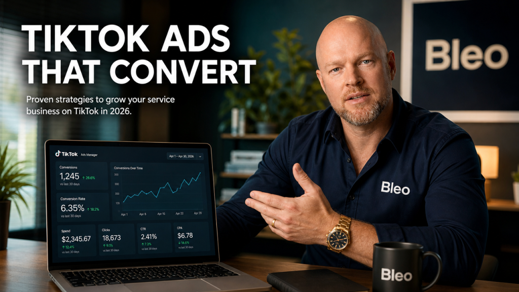 A marketing professional at a desk reviewing TikTok Ads analytics dashboard showing conversion metrics and campaign performance, wearing a Bleo-branded navy shirt